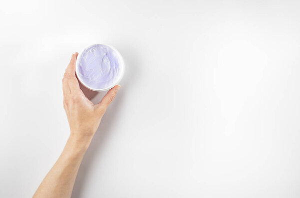 Woman's hands holding purple moisturizing cream with bakuchiol ingredient. Flat lay, copy space.