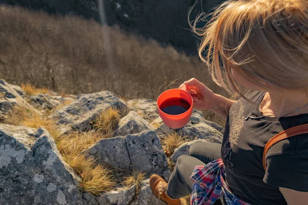 崖の端にあるコーヒーを飲みながらリラックスした若い女性ハイカーは 美しい山々の景色と日没を楽しんでいます 頭上からの眺めコピースペースハイキング旅行のコンセプト — ストック写真