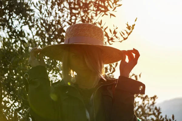 年轻的女人戴着草帽对着相机笑. 夕阳西下 欢乐时光旅行的概念. — 图库照片