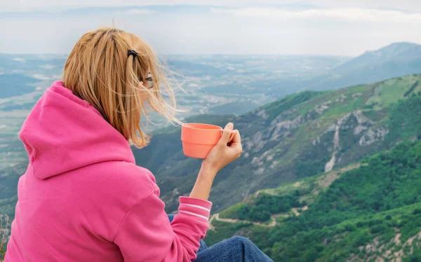 山頂からの眺めながらホットドリンクを楽しむ若い千年紀の女性 トレッキングコンセプトの中でリラックス — ストック写真