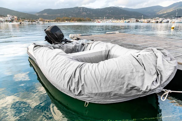 Moored inflatable boat covered with case at the pier.