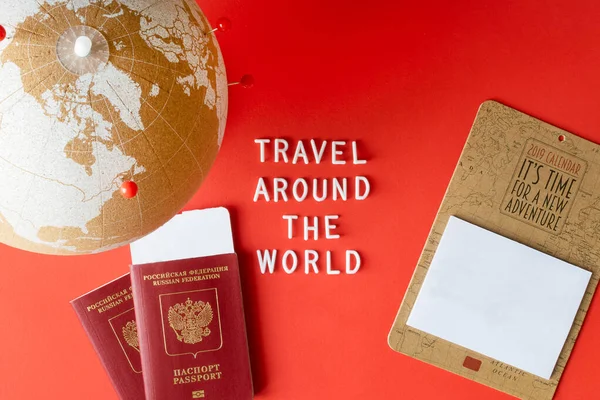 Globo de cortiça com alfinetes vermelhos, calendário de mockup em branco e passaportes com bilhete e texto "Viaje pelo mundo". Conceito de viagem mundial. Flat lay, espaço de cópia . — Fotografia de Stock