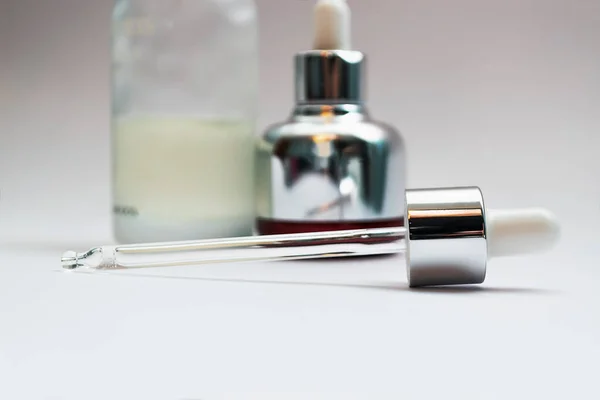 Close up on glass skincare pipette and unfocused cosmetics bottles on background. Bakuchiol concept. Luxury skincare products concept. — Stock Photo, Image