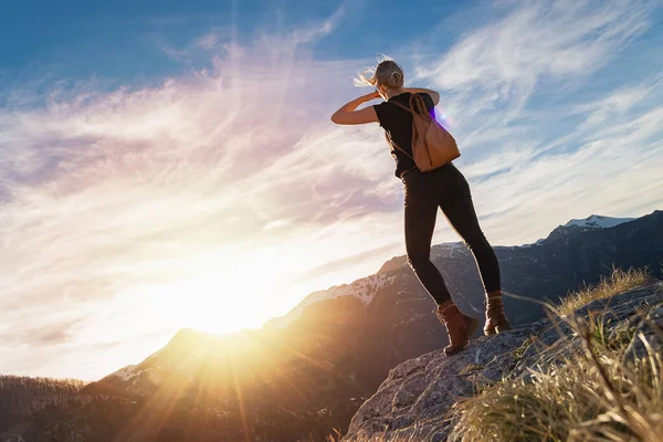 背着背包的年轻女子站在岩石悬崖的边缘 凝视着山中的落日 徒步旅行的概念 复制空间 — 图库照片