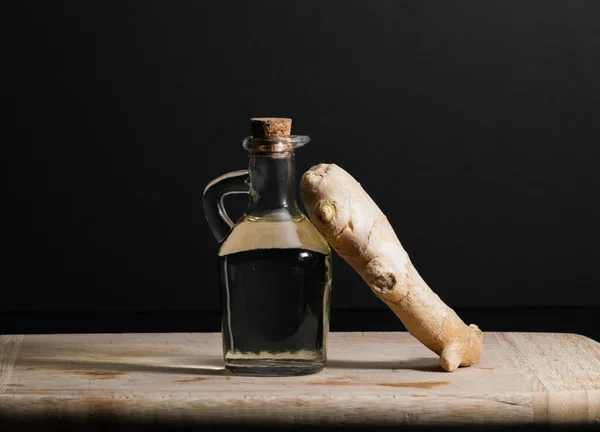 Ingefärsoljeflaska med ingefärsrot på träskärbräda. Hälsosam kost koncept. — Stockfoto