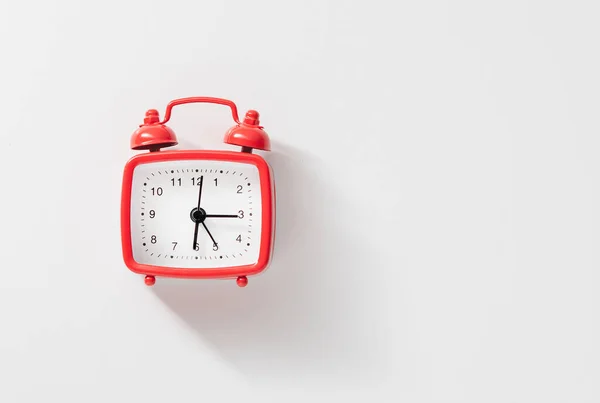 Beyaz arkaplanda kırmızı alarm saati, yukarıdan görünüm.