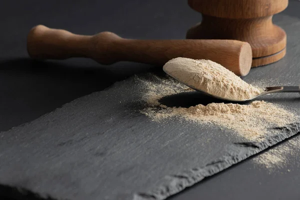 Taş kesme tahtası yüzeyi ve siyah arka plan üzerinde Maca tozu ve ahşap pounder. Süper yiyecek maca ilave konsepti. Boşluğu kopyala
