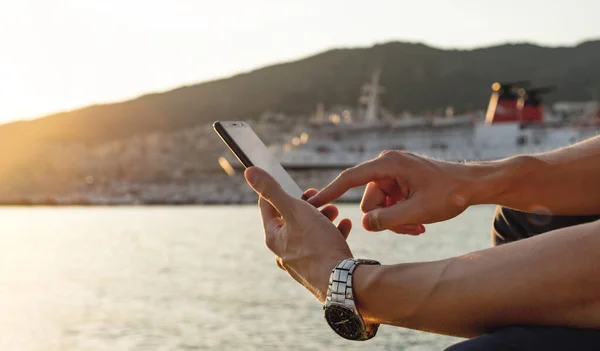 Man Sitting Sea Holding Smartphone Booking Sea Trip Online Sunset — Stock Photo, Image