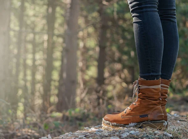 Deri çizmeli kadın bacakları ormanı yakından görüyor, arka planda odaklanmamış ağaçlar var. Yürüyüş turizmi. Dağlardaki orman. Boşluğu kopyala.