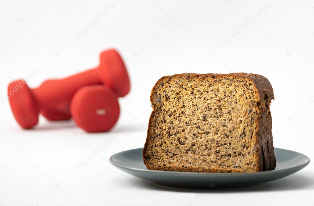 Fitness protein bread and unfocused red dumbbells on background. Helthy lifestyle sports concept.