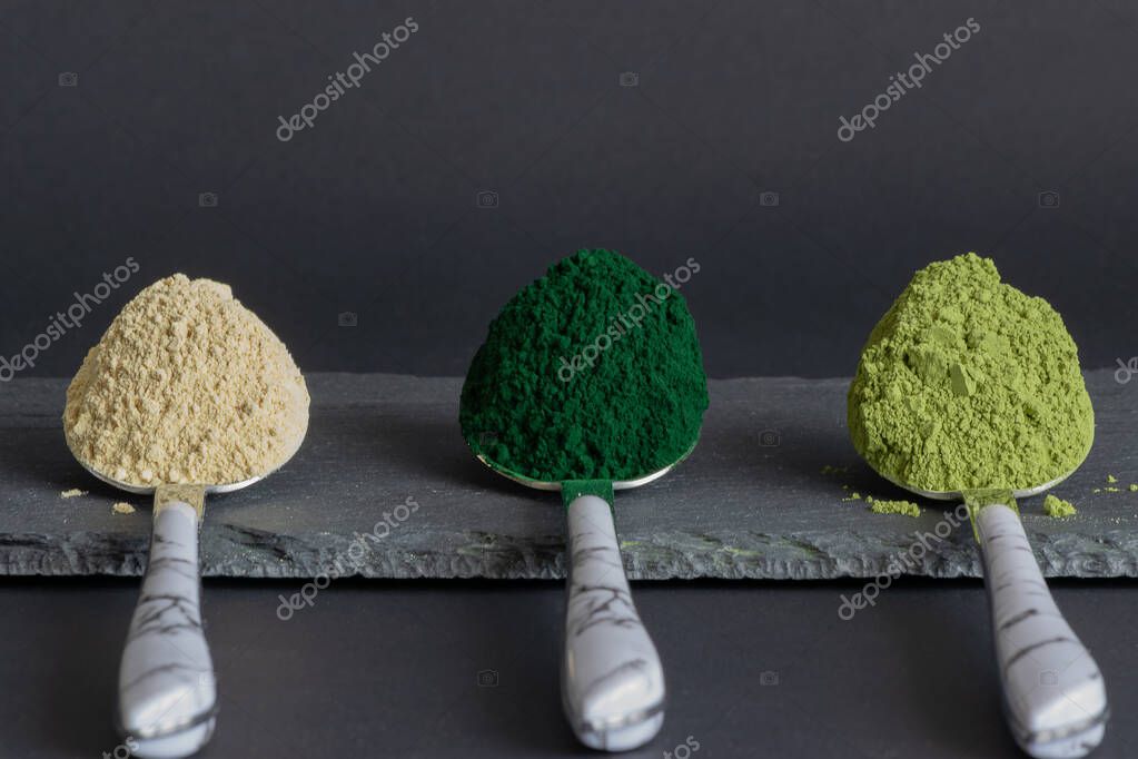 Cucharas con espirulina, matcha y polvos de maca sobre tabla de piedra
