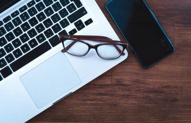 Masada dizüstü bilgisayarı ve akıllı telefonu olan gözlük - iş konsepti