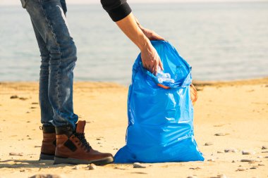 Plajda plastik şişe toplayan kadının yakın görüntüsü.