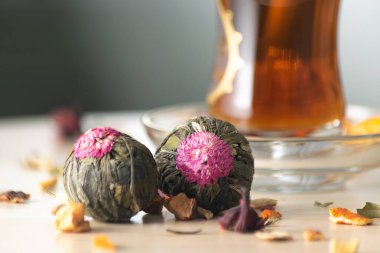 Çiçekli yasemin yeşil çay topları ve arka planda odaklanmamış Türk çayı ile karışık çay otları. Asya çay zevki kavramı.