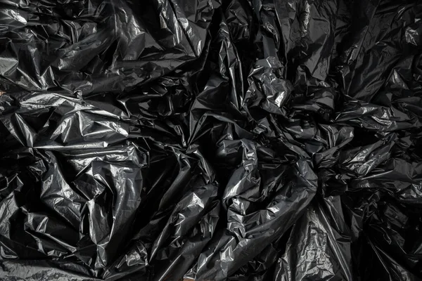 Siyah plastik torbalar arka plan dokusu düzdü. Plastik kirliliği sorunu kavramı. Boşluğu kopyala, arkaplan şablonu.
