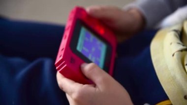 Kavala, Yunanistan - 11 / 15 / 2019: Kırmızı renkli 8-bit konsolu oynayan çocuk, 