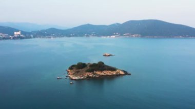 İnsansız hava aracı, kayalık ıssız bir adanın üzerinde akşam vakti uçarken görülüyor..