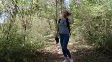 Sırt çantalı genç bir kadın nehir kenarında yürüyüş yapıyor. Eğleniyor..