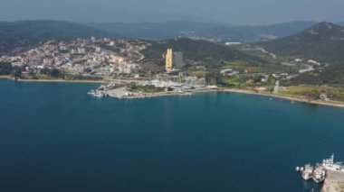 Gün batımında arka planda deniz, rıhtım ve dağların üzerinde uçan insansız hava aracı videosu