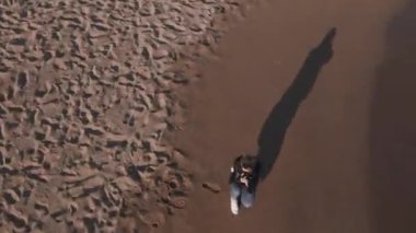 DSR kameralı kadın fotoğrafçı gün batımında boş sahilde fotoğraf çekiyor..