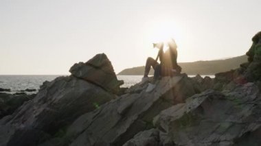 DSR kameralı kadın fotoğrafçı gün batımında boş sahilde fotoğraf çekiyor..