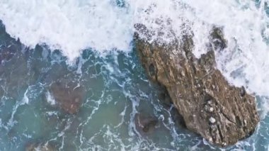 Deniz dalgalarının sert kayaları parçaladığı hava görüntülerini kapatın.. 