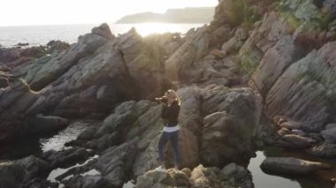 DSR kameralı kadın fotoğrafçı gün batımında boş sahilde fotoğraf çekiyor..