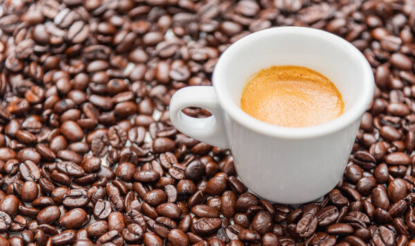 Close up cup of espresso coffee and whole roasted coffee beans, copy space