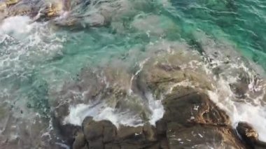 Deniz dalgalarının sert kayaları parçaladığı hava görüntülerini kapatın.. 
