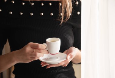 Penceresinde espresso bardağı olan kadın, yumuşak güneş ışığı, lüks yaşam tarzı, kopyalama alanı..