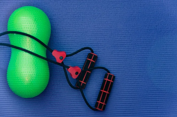 Rubber resistance bands and small peanut shaped exercise ball at fitness mat.