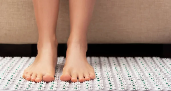 Female feet on acupressure mat. Alternative medicine and home-massage concept