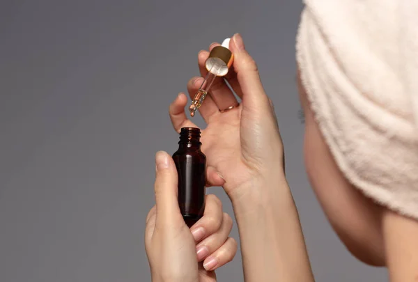 Elinde cam bir şişe güzellik serumu tutan kadın. Cilt bakımı için güzellik ürünü