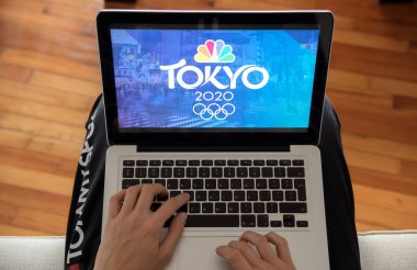 Kavala, Yunanistan - 01 Aralık 2019: Tokyo 2020 Olimpiyat Yaz Oyunlarını evde dizüstü bilgisayarda izleyen adam. 