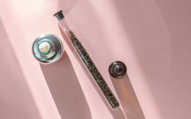 Babchi kuru çiğ tohum (Psoralea Corylifolia) ve pembe arka planda bakuchiol cilt bakım kremi. Düz döşeme, ürün modelleme, kopyalama alanı. Bakuchiol kozmetik konsepti. 
