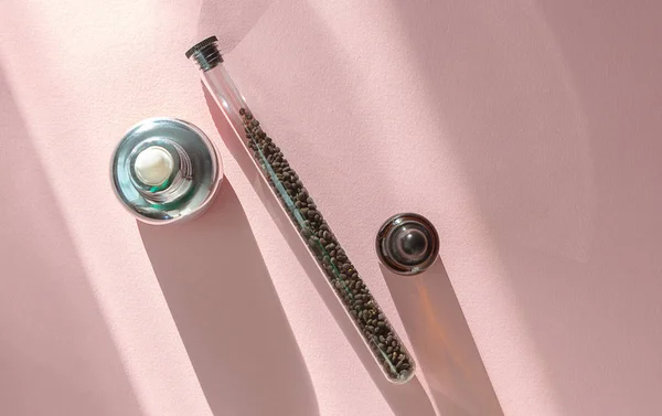 Babchi kuru çiğ tohum (Psoralea Corylifolia) ve pembe arka planda bakuchiol cilt bakım kremi. Düz döşeme, ürün modelleme, kopyalama alanı. Bakuchiol kozmetik konsepti. 