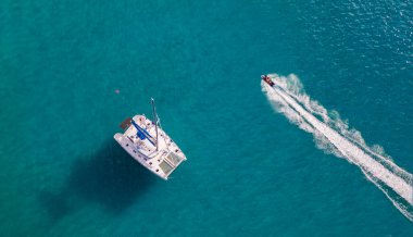 Beyaz yelkenli ve turkuaz okyanusta jet-ski manzarasının hemen üstünde..