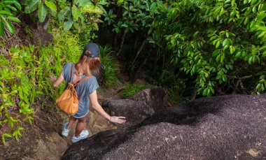 Sırt çantalı sağlıklı bir kadın kayaların arasına tırmanıyor.