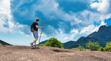 Sırt çantası ve tahta sopayla mavi gökyüzüne tırmanan adam.. 