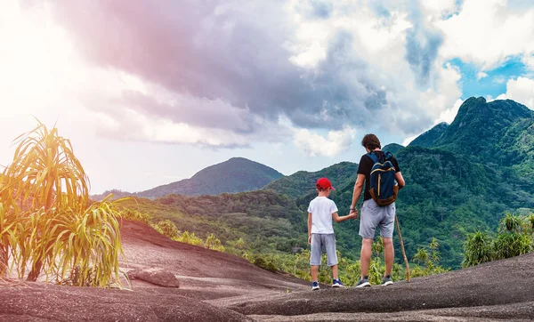 子供の手を握って観光客の男は 風光明媚な熱帯の山々や森の景色を見て — ストック写真