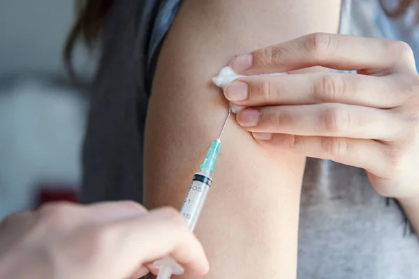 Making vaccine injection to woman, close up syringe with needle.