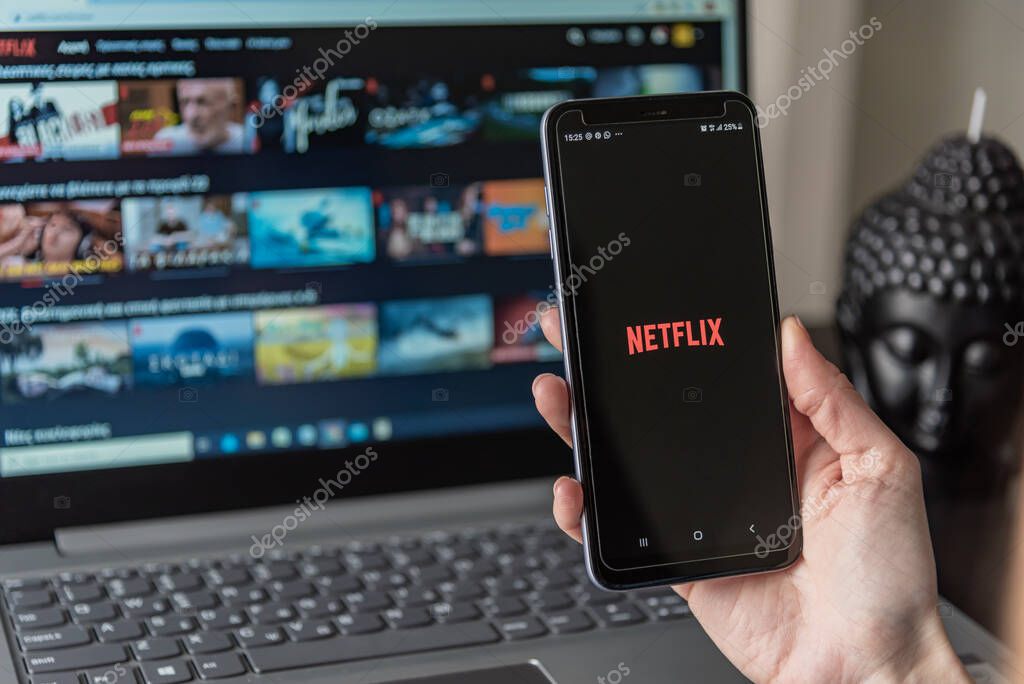 Thessaloniki, Greece - May 3, 2020: Netflix smartphone application of the phone screen, woman holding phone with Netflix app.