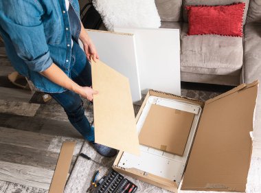 Genç adam kutuları açıyor ve ev için DIY mobilyaları var.