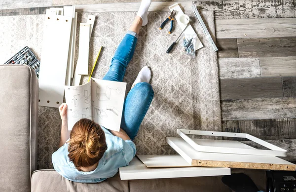 Mujer Joven Concentrada Leyendo Las Instrucciones Para Montar Muebles Casa —  Fotos de Stock