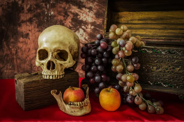 Natureza morta com um crânio humano com maçãs e uvas falsas — Fotografia de Stock