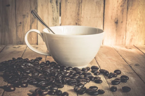 Coffee cup and coffee beans on old wooden background — Stock Photo, Image