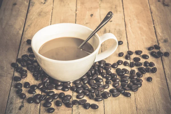 Coffee cup and coffee beans on old wooden background — Stock Photo, Image