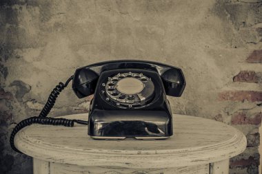 Vintage black phone on old walls background 