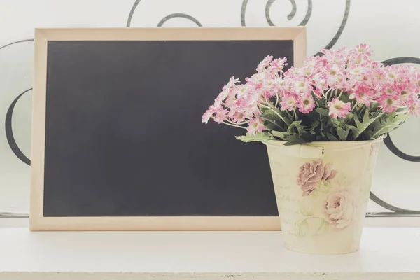 A small blackboard and a bouquet of colorful flowers in a vase