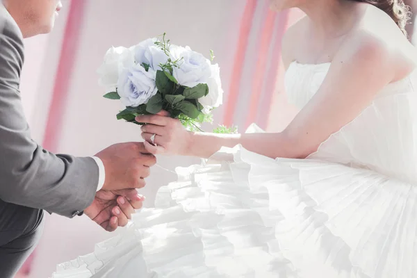 Bride and groom holding hands and a bouquet of beautiful flowers — Stock Photo, Image